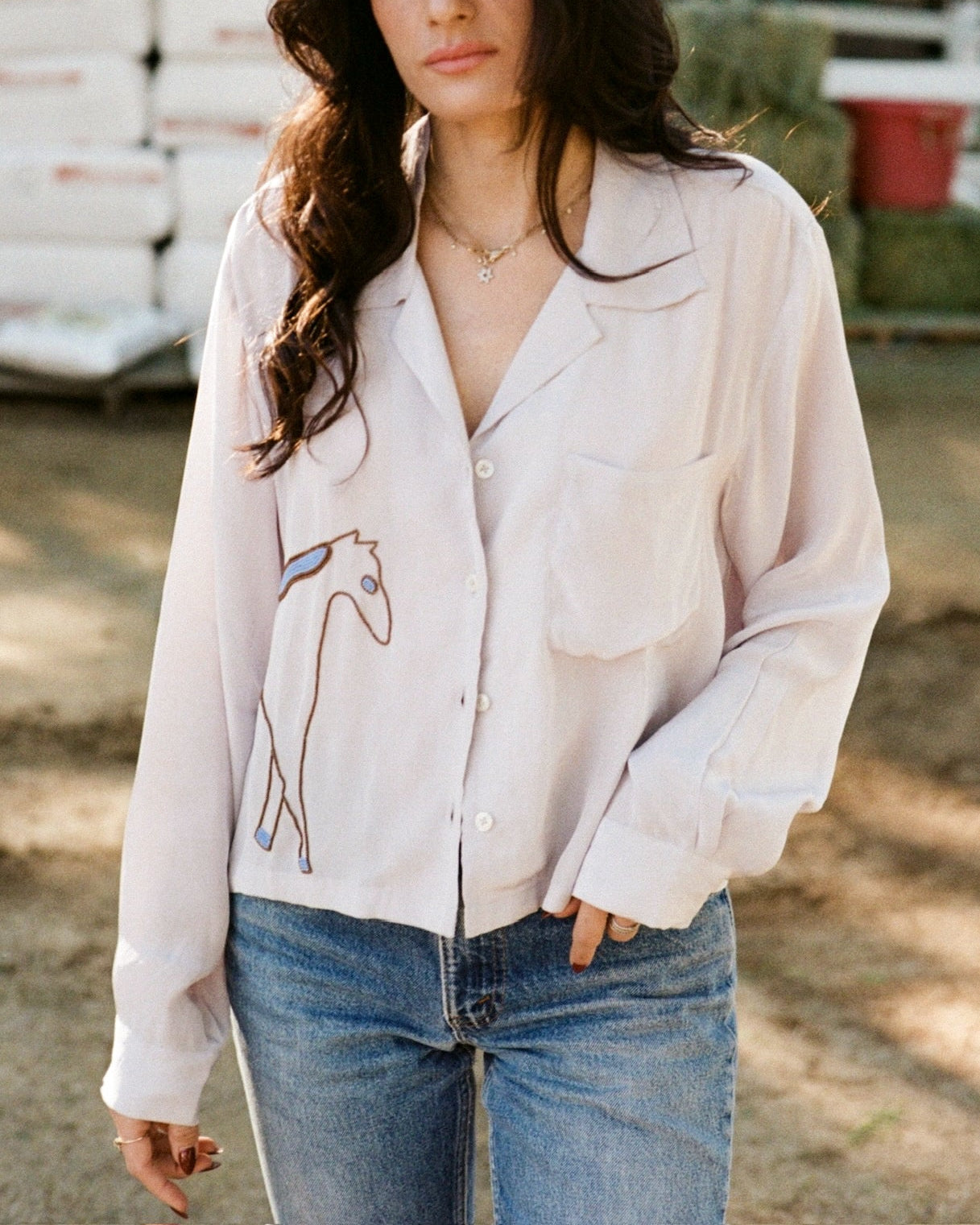 Woman wearing a light-colored shirt with a horse graphic design outdoors